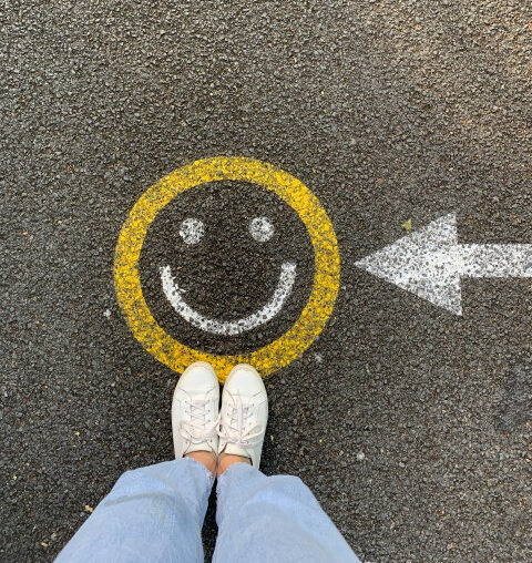 young person standing on picture of smiley icon