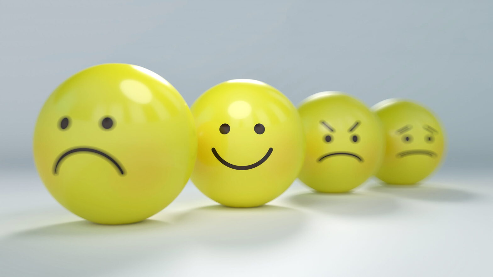 four yellow balls with different emoji expressions penned onto them